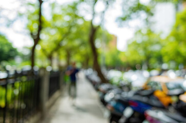 Fototapeta premium Blurry urban sidewalk with trees and parked cars.