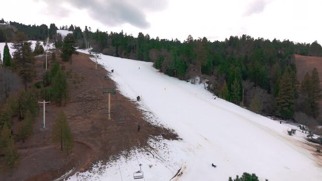 Wide overview of Lake ski area with patchy snow trails cutting through forested hills