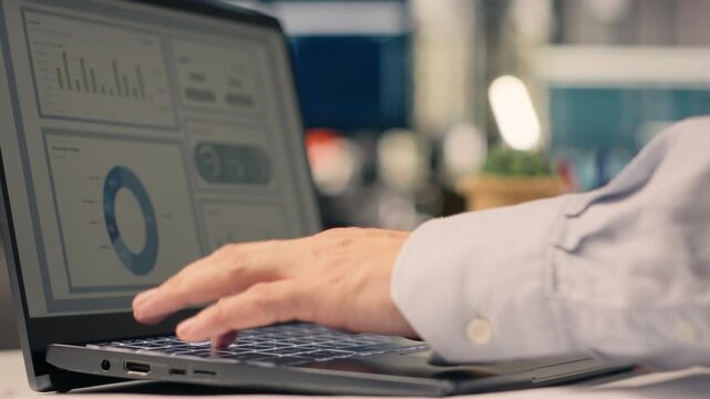 Worker analyzes business intelligence and monetary data on laptop. Visual data, performance metrics and insights guide objectives and organizational planning in a multinational company.