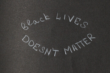 Fototapeta premium Black Lives Doesn't Matter written in chalk on a dark textured surface