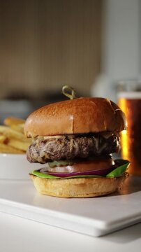 Slow tracking shot of a hamburger, French fries and beer at a restaurant bar. Shot in HD vertical video. 