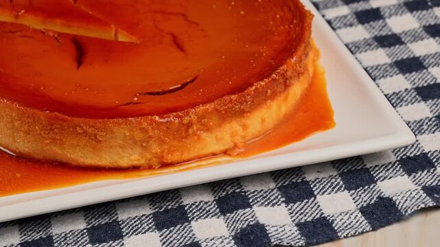 Aerial view of a traditional homemade flan on a kitchen table with a rustic checkered tablecloth