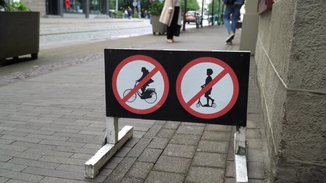 A street sign forbids riding bikes or scutters on a side walk