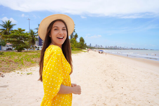 Portrait of smiling woman with yellow sundress on Cabo Branco beach, Joao Pessoa, Brazil
