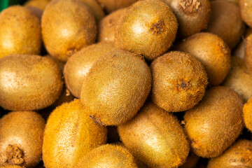 Detail of ripe kiwis stacked at a market stall, representing a healthy eating concept.