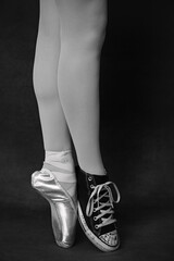 A ballerina’s feet, wearing one pointe shoe and one sneaker.  © Holly
