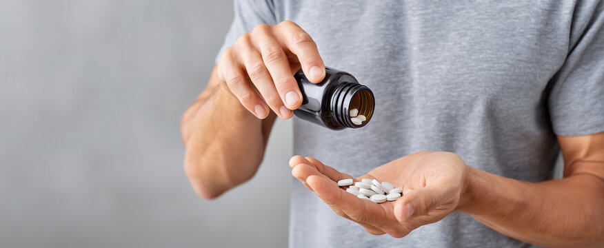 Person pouring white diet pills into hand from black bottle in simple indoor setting during the day