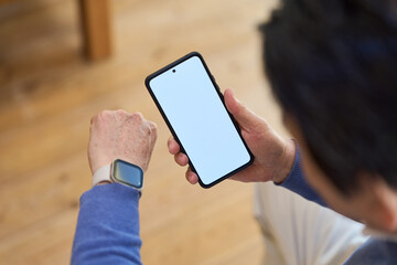 スマートデバイスで健康管理をするアジア人シニア男性