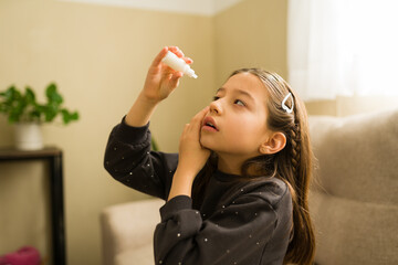 Girl applying eye drops at home, treating eye irritation or allergy, health and vision care for children