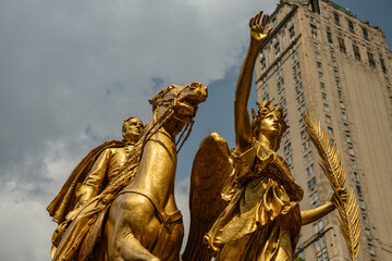 Close-up view of the golden General Sherman statue in Grand Army Plaza, New York City. The sculpture depicts the general on horseback with a winged female figure holding a palm branch.