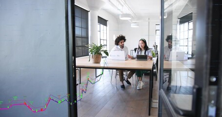Collaborating colleagues working on laptops at office table, button-up shirt, green pants, plant © vectorfusionart