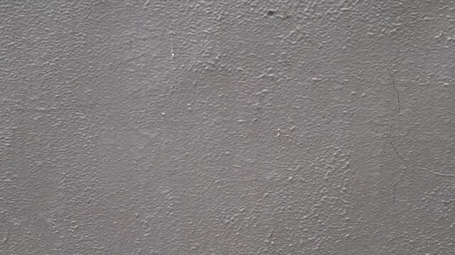 Rainwater streaming down concrete surface texture. Wet cement wall with flowing liquid pattern. Urban exterior soaked by rainfall motion backdrop. Minimal gray facade during heavy weather scene.