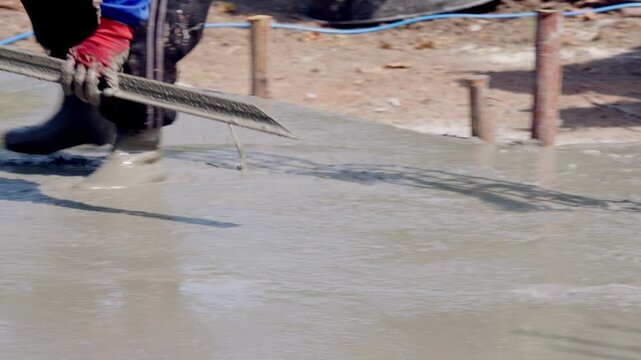 Close up of construction worker preparing concrete foundation for real estate project. Professional builder leveling cement surface to ensure stable and long lasting building structure.