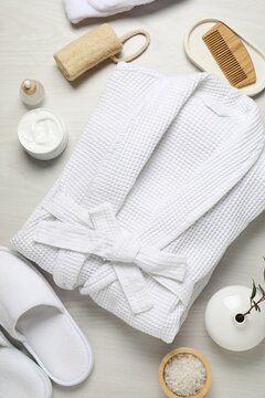Flat lay composition with bathrobe and spa essentials on white wooden background