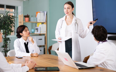Fototapeta premium Qualified female doctor speaks in front of a young team of doctors who are preparing for practice and internship