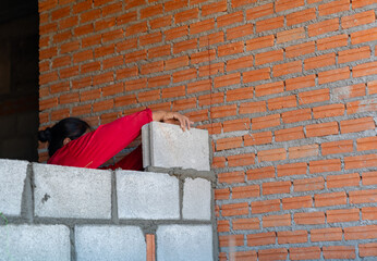Professional bricklayer building a brick wall with mortar and trowel.