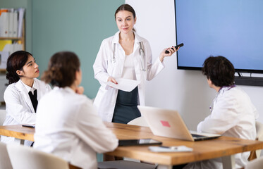 Fototapeta premium Qualified female doctor speaks in front of a young team of doctors who are preparing for practice and internship