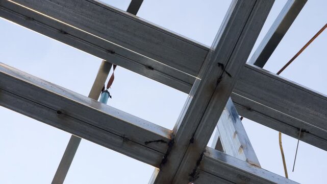 Low angle view of industrial steel structure frame with visible welding joints and metal beams against clear sky. Construction engineering concept with copy space, strong architecture background.
