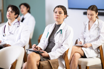 Young woman at a medical conference for doctors, she listens to a lecture and looks at a...