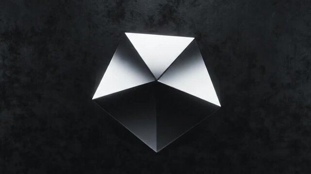 Close-up shot of a metallic origami-like geometric shape with sharp folds and a gradient of light to dark silver tones, set against a dark textured background with a cinematic lighting effect.