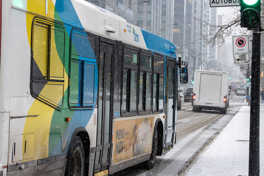 Canada, Montreal, 23 December 2025 : Snowy city street, public bus, stop sign, green light.