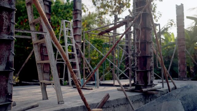 Concrete column formwork and scaffolding at building construction site. Structural engineering process and foundation preparation in outdoor environment.