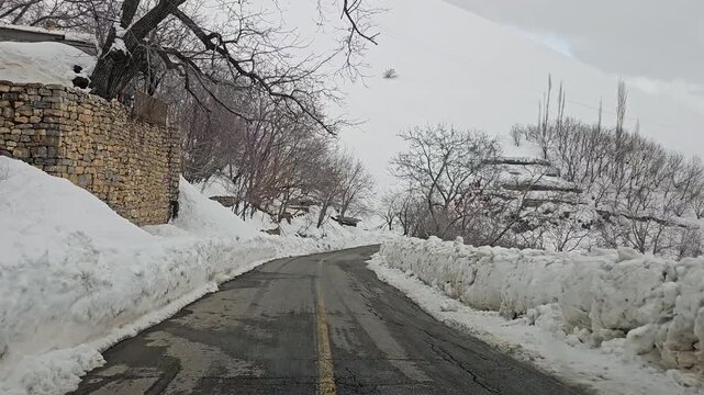 enjoying a winding snow-covered rural mountain road lined with snowbanks and bare winter trees, stretching through a quiet snowy landscape under an overcast sky.
📍Hawraman Takht, Kurdistan 