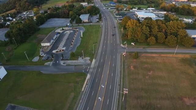 Vertical Screen Aerial Highway Curve Through Rural Landscape At Twilight Johnson City Tennessee, Crescent Motel With Parking, Empty Lanes, Grassy Lots, Tree Line, Soft Sunset Glow, Tranquil