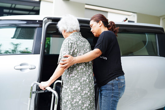 Caregiver help Asian elderly woman disability patient get in her car.