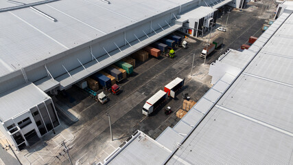 Naklejka premium Aerial view modern warehouse for trucks unloading and loading, semi truck cargo trailer at logistic park warehouse, Distribution warehouse shipping supply chain, Business transportation logistic.