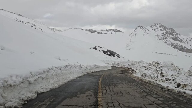 A narrow snow-covered mountain road winding between tall snowbanks and distant snowy peaks under a cold, overcast winter sky.
📍Hawraman Takht, Kurdistan 