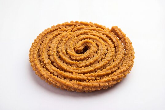 Single golden brown spiral chakali indian snack on white background