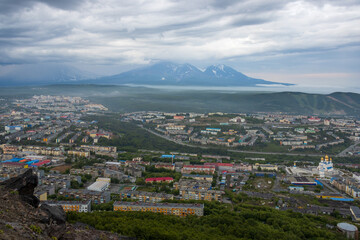 Beautiful cityscape. Top view of the cathedral, buildings and streets. Volcanoes in the distance. Overcast weather. Low clouds. City of Petropavlovsk-Kamchatsky, Kamchatka Territory, Russian Far East.