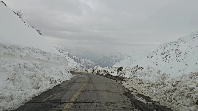 A twisting snow-covered mountain road bordered by high snow walls, winding through snowy hills and rugged peaks under a cold, overcast winter sky.
📍Hawraman Takht, Kurdistan 
