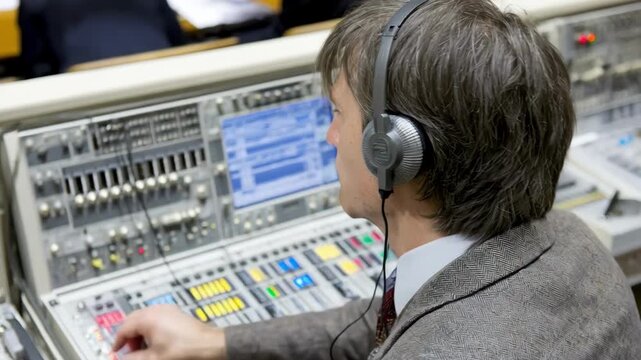 Medium shot of a courtroom technician adjusting closed caption equipment to ensure accurate live transcription during a legal proceeding.