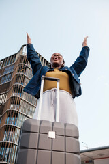 Young black woman celebrating successful arrival at airport with suitcase