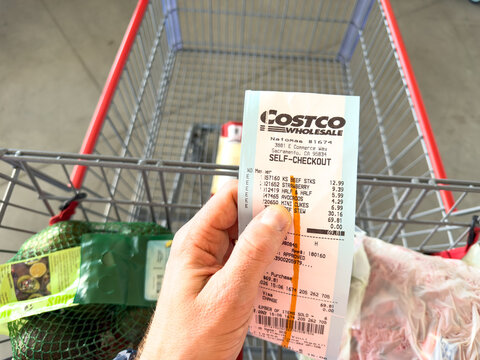 Costco Wholesale Self Checkout Receipt Held Over Shopping Cart