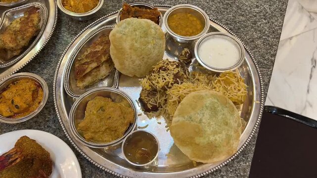 Traditional Bengali wedding thali with peas kachori, baked bhetki fish, biryani, prawn fry, and lentils.