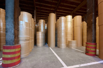 Paper rolls stored in a spacious warehouse of a paper mill located in an industrial area