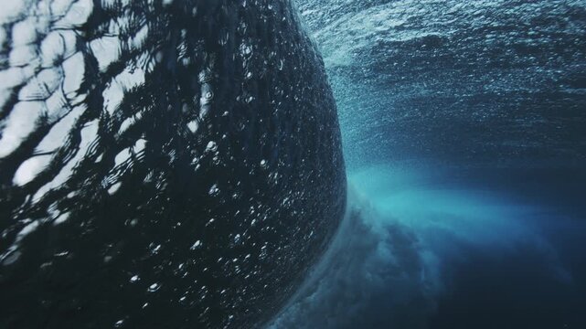 Curved underwater wave face with dramatic shadow and deep ocean blue texture