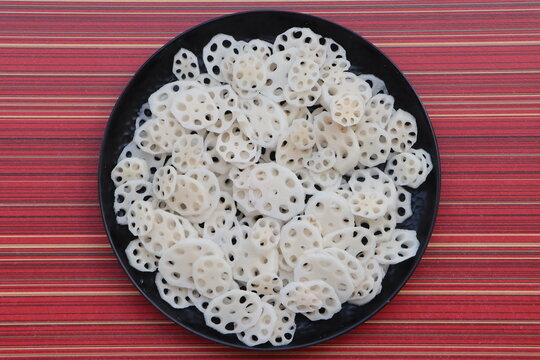 Fresh raw lotus root slices on a plate, cooking ingredient