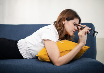 Obraz premium Woman removing her glasses and touching her forehead in discomfort, representing eye strain, headache, fatigue, or vision problems for health and wellness content.