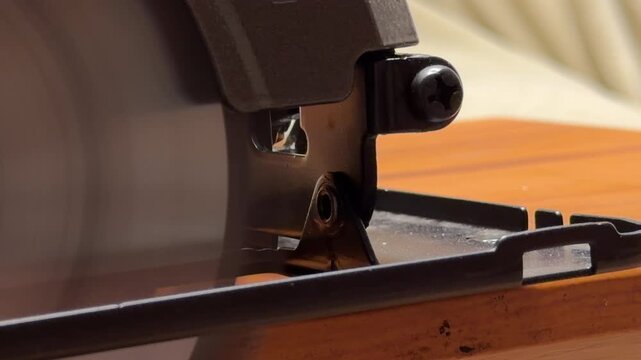 An industrial circular saw is switched off, causing the spinning blade to gradually lose speed. This deceleration produces a fading metallic whir until the motor reaches a silent halt.