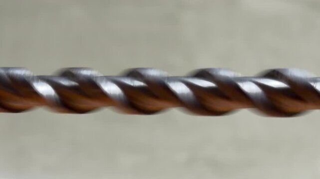 A metal drill bit spins at high velocity against a neutral background. The rapid rotation generates a consistent mechanical hum and a sharp, metallic whirring noise.