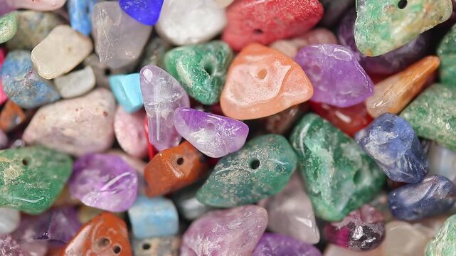 Rotating slowly pile of colorful semi-precious gemstone beads and healing crystals, Close-up shot