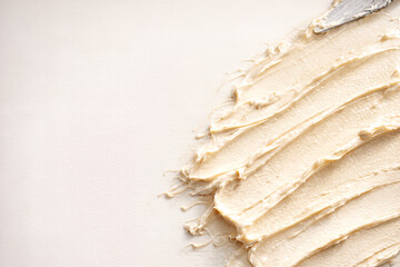 Creamy cosmetic texture spread with palette knife on textured surface