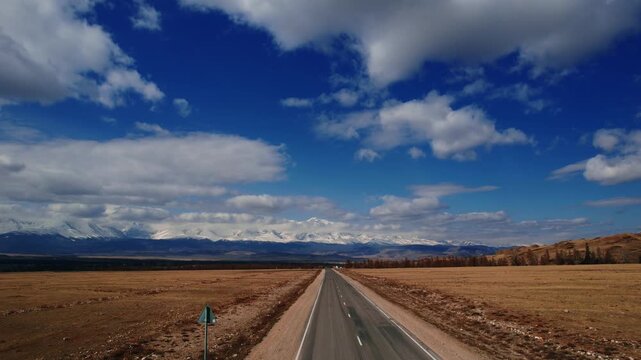 Beautiful landscape road in autumn forest with snow peaks mountains Chuysky tract, Altai Kurai steppe Russia. Aerial top view.