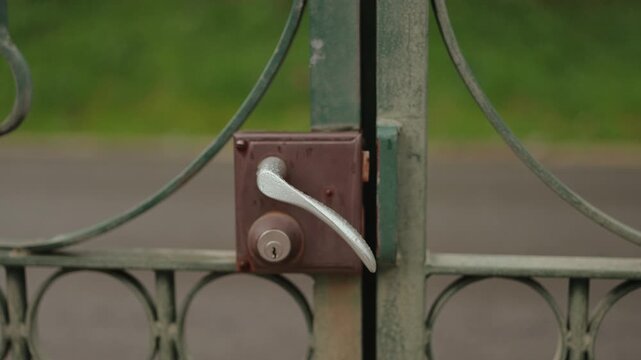 Close up of metal gate lock and handle on outdoor fence