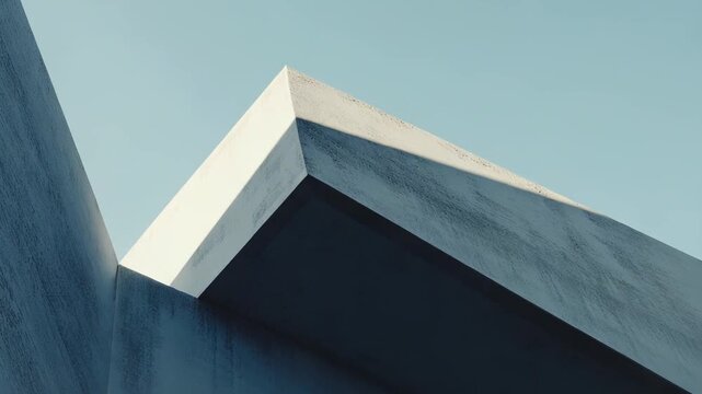 Modern architecture featuring abstract concrete building elements with geometric shapes and stark lines under a light blue sky with clouds, creating a minimalistic composition of light and shadow
