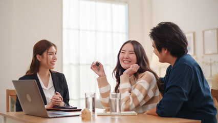 Happy Asian couple receiving new house key from real estate agent at home